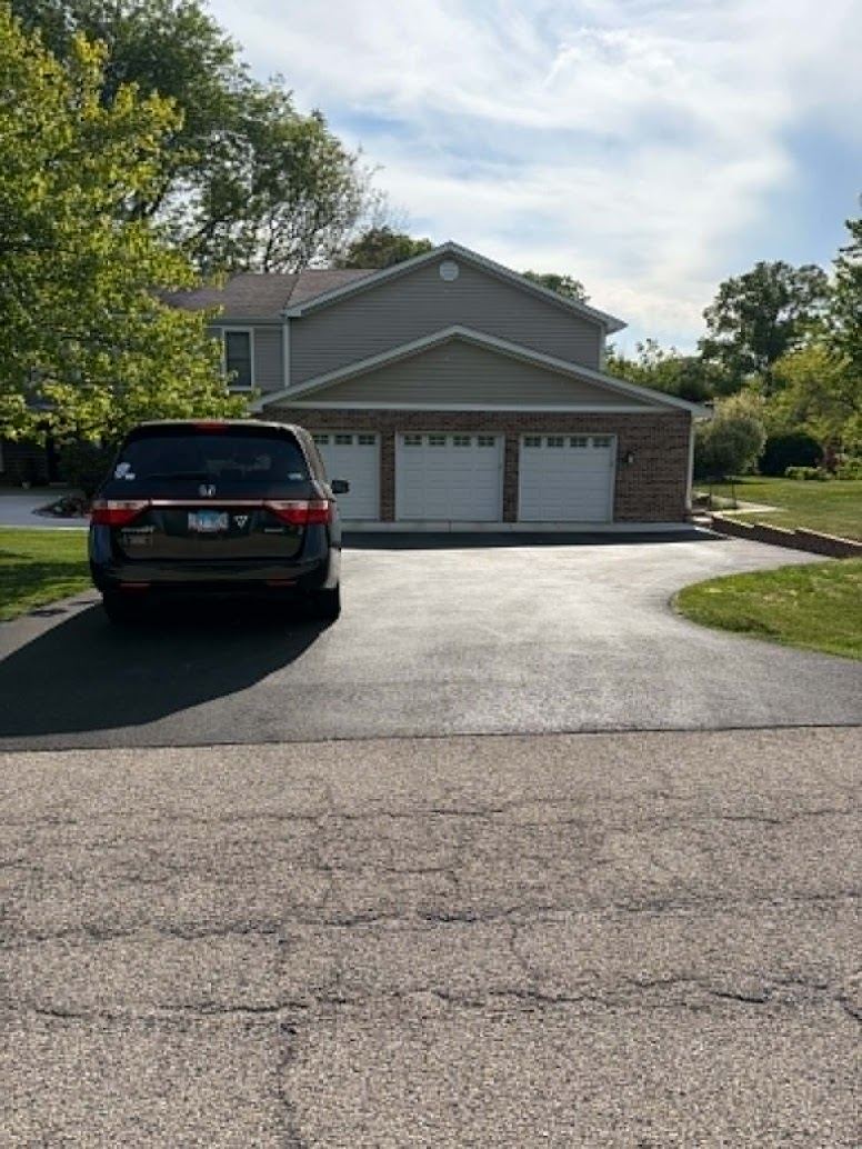 Fresh asphalt driveway leading to a three-car garage installed by G&D Construction